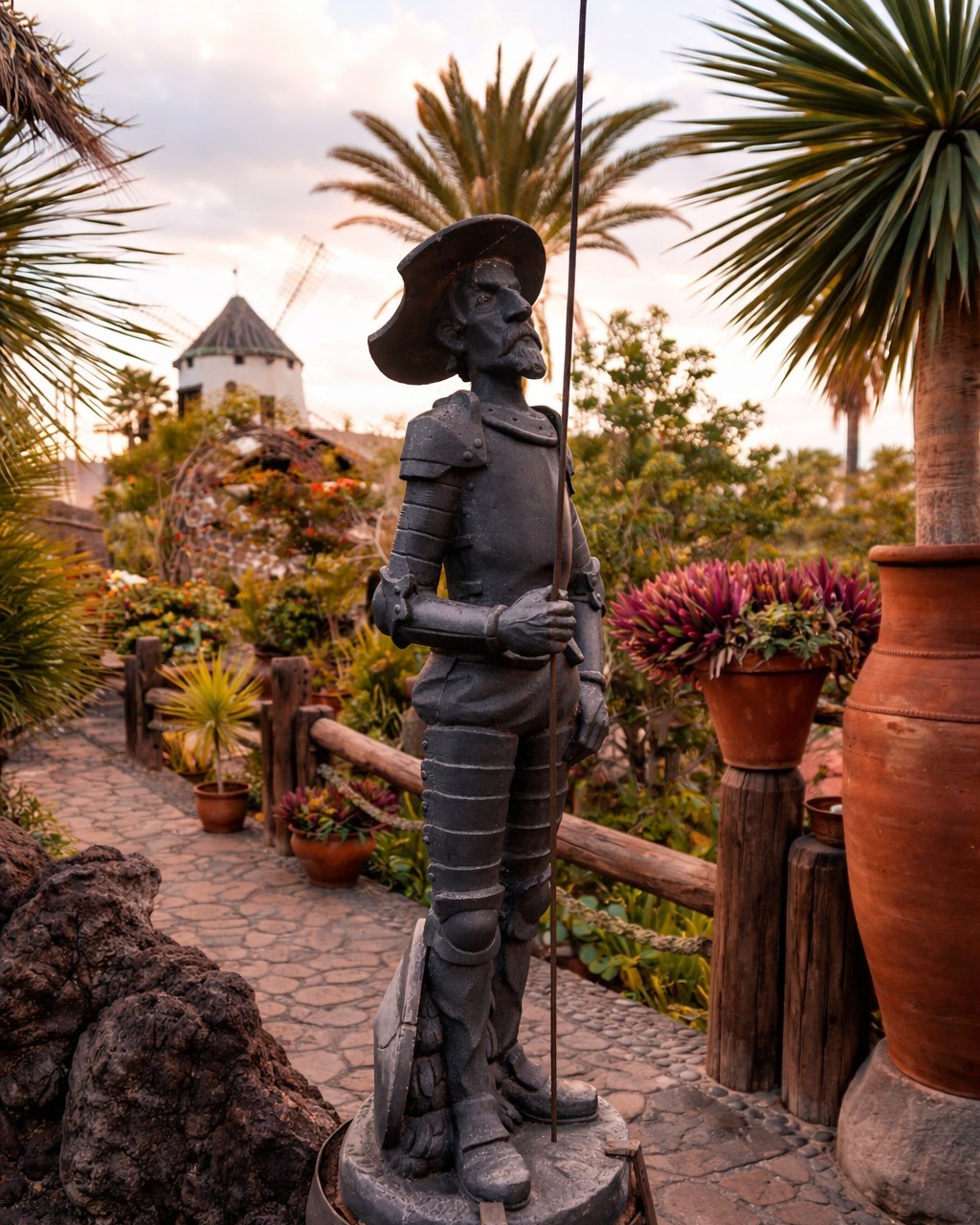 Don Quixote statue in the garden of El Molino Blanco with the windmill behind
